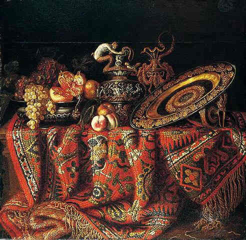 A still life of peaches, grapes and pomegranates in a pewter bowl, an ornate ormolu plate and ewers, all resting on a table draped with a carpet